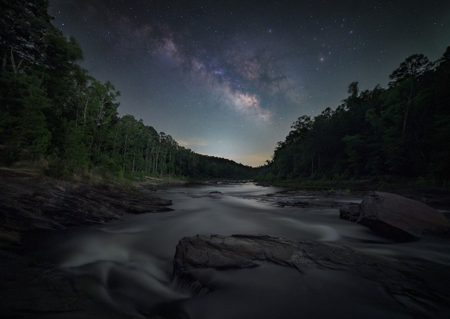 Milky Way over a river with wooded banks, a blend of a long foreground exposure and a stacked sky