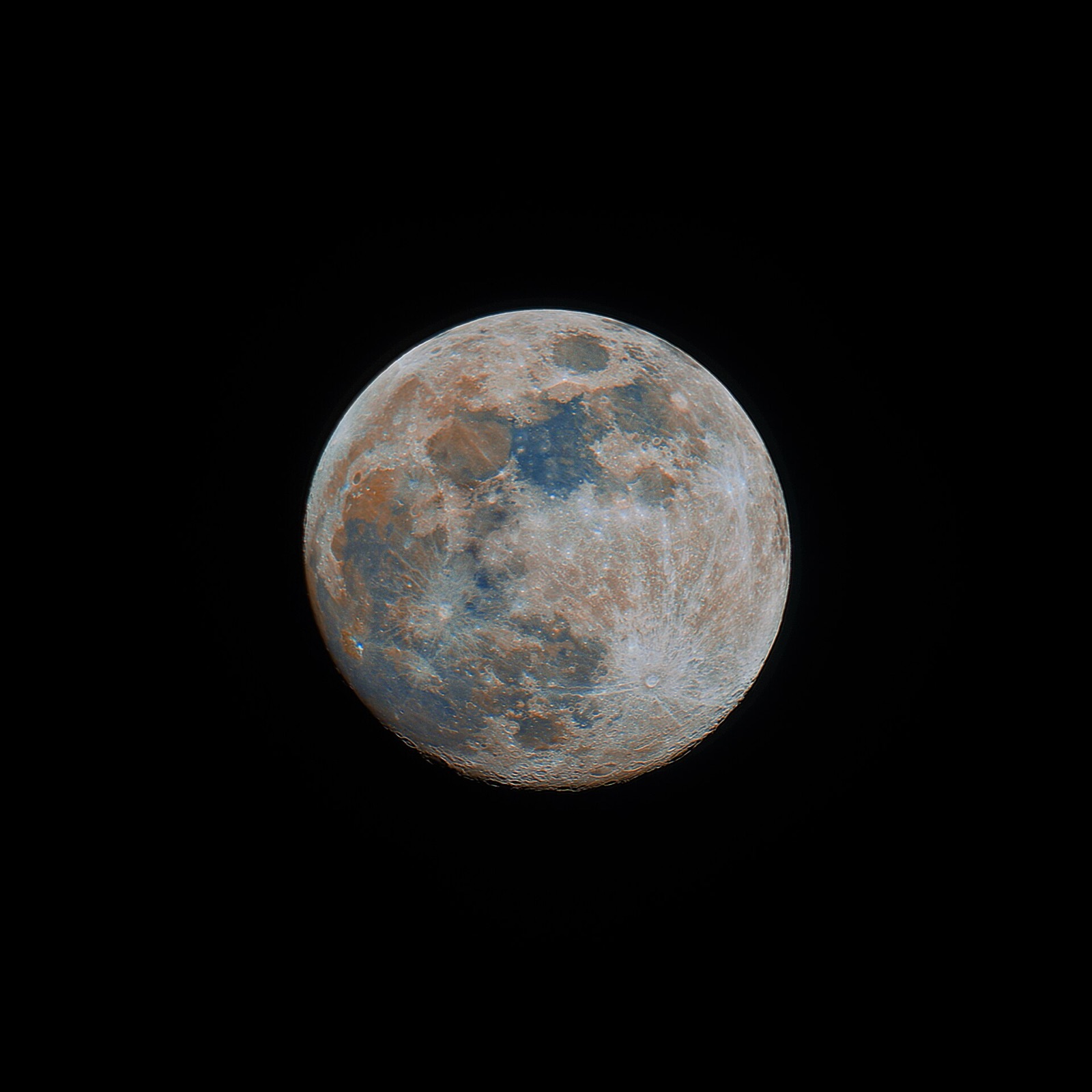 Full Moon with boosted colour showing blue and rust-brown patches across the dark seas.