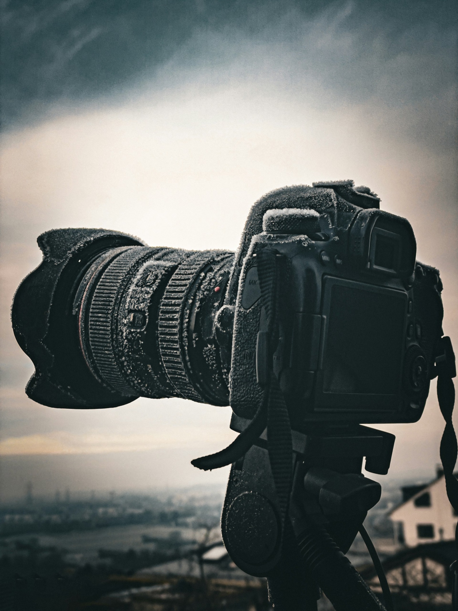 DSLR camera and lens on a tripod covered in a layer of frost