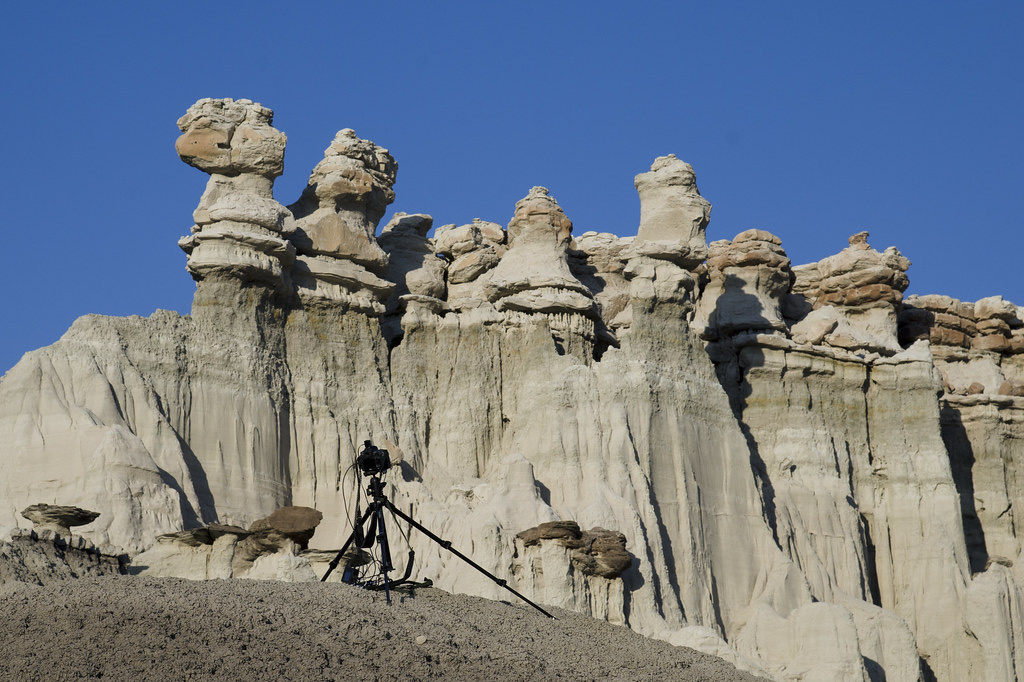 Camera on a low tripod with a controller and cables, set up in front of desert rock formations