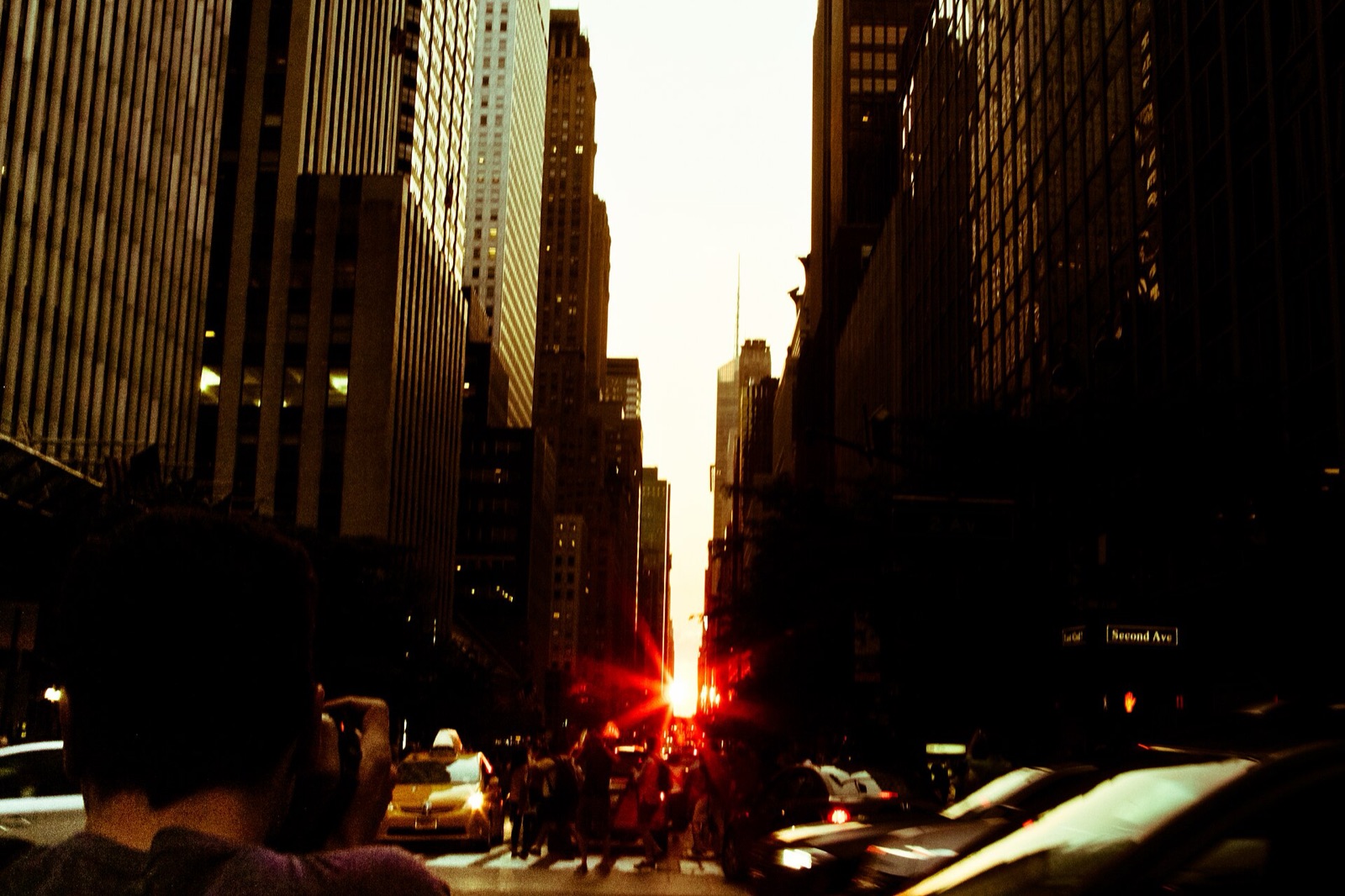 Setting Sun with star-shaped rays at the end of a Manhattan street between dark towers.