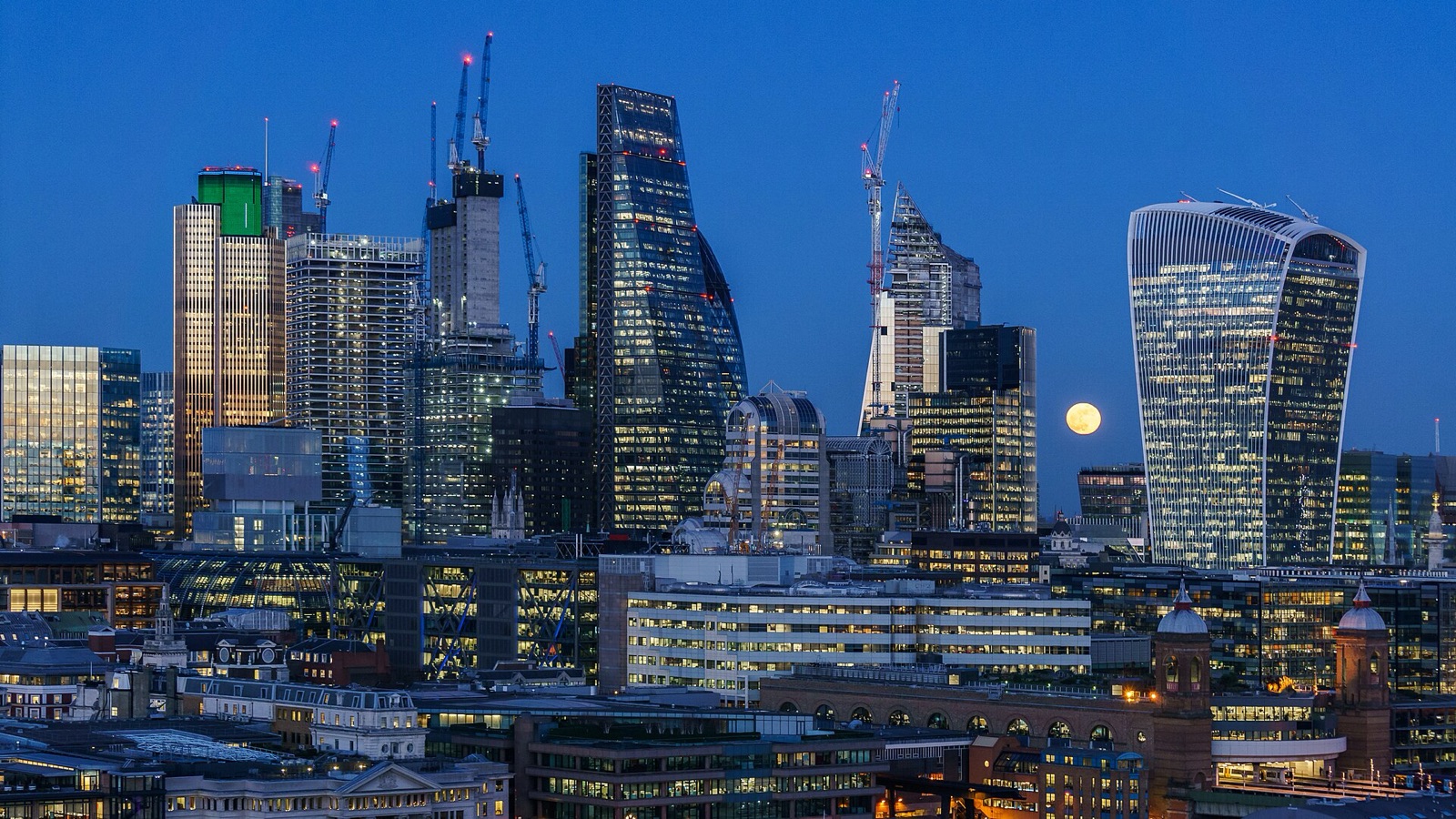 City of London skyscrapers at blue hour with a small full Moon between the towers.